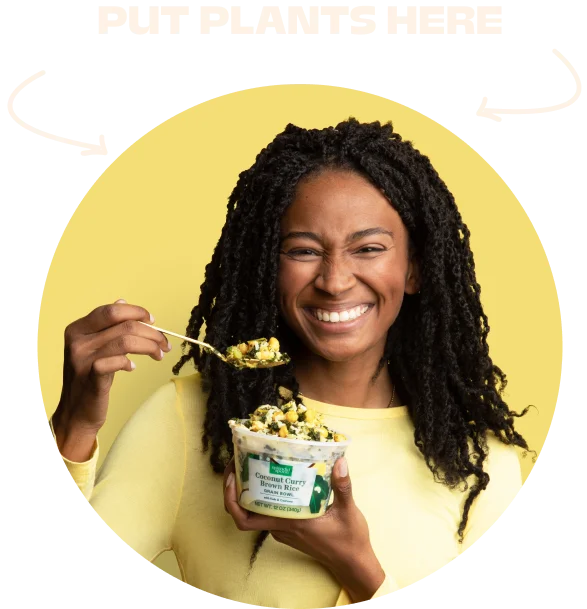 A woman in yellow, smiling and holding up a spoonful of Splendid Spoon.