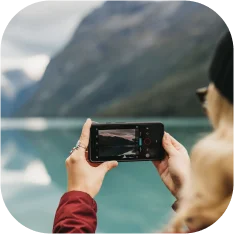 woman taking a picture with her phone of a glacial lake