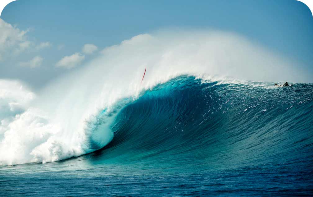 The tremendous force of a crashing big wave throws a red surfboard over the windswept lip.