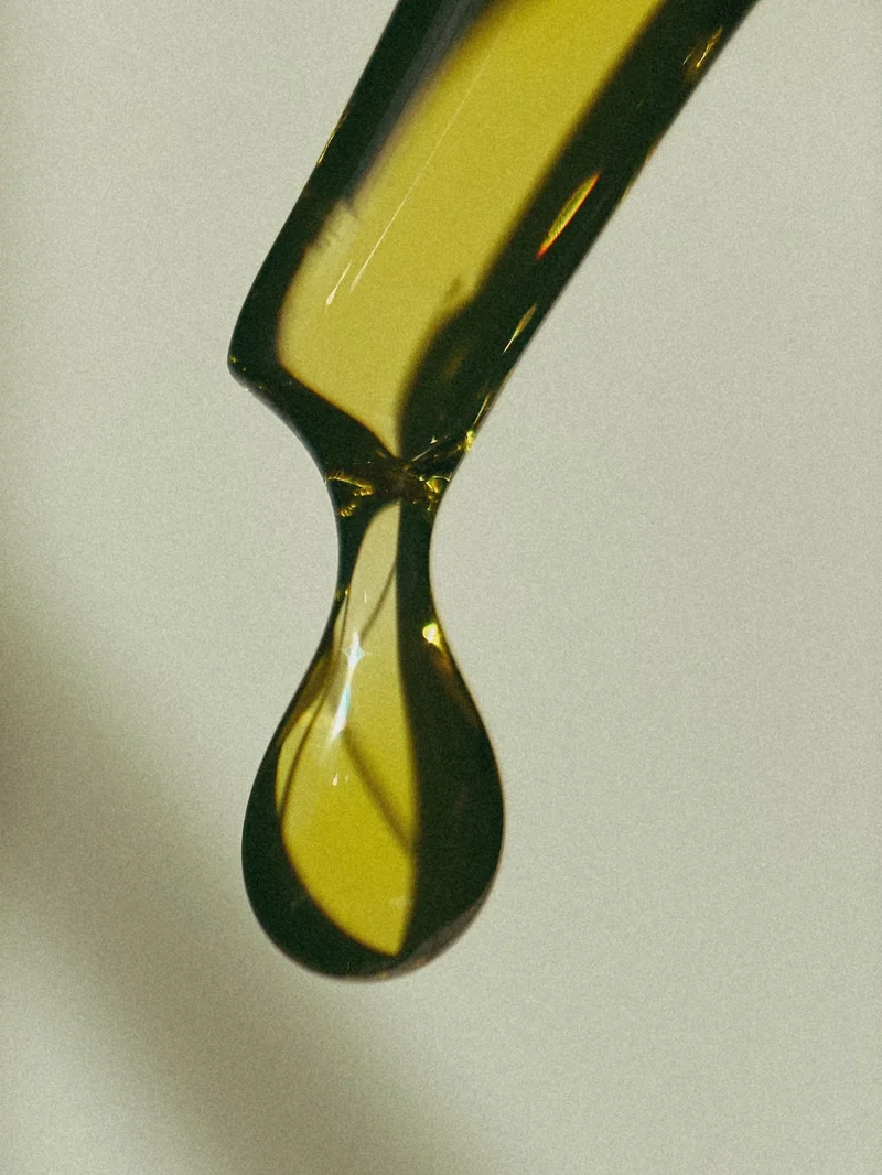 A zoomed in photo of a drop of face oil from a glass dropper.