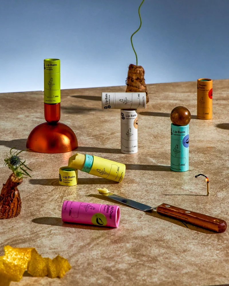 A collection of rainbow paper lip balm tubes stacked and arranged with colorful objects