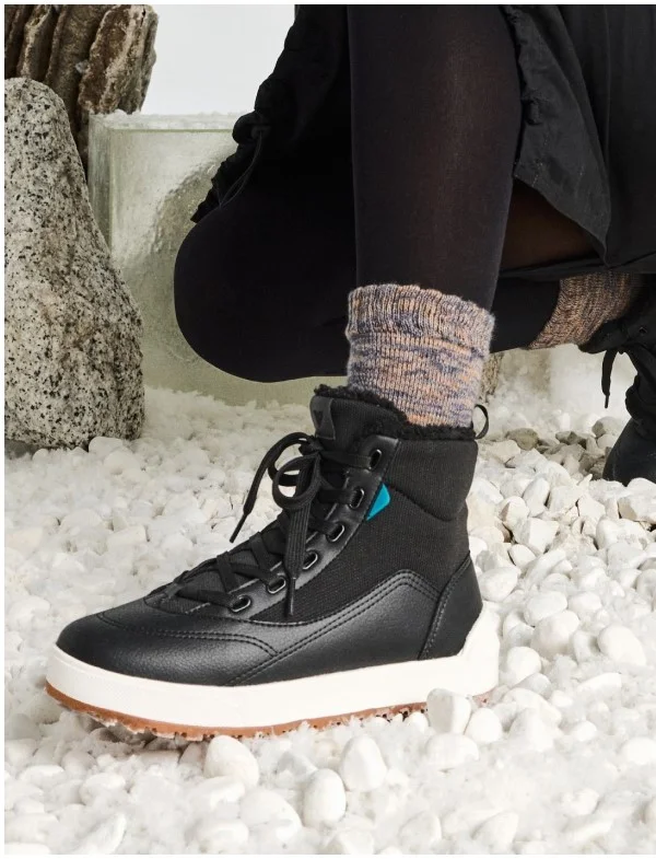 Picture of a female model putting on the Alta High Top.