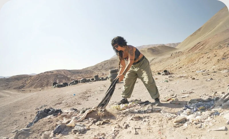 A person pulling on a piece of clothing buried in the sand.