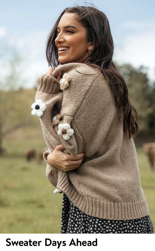 A woman wearing a sweater with floral appliqués.
