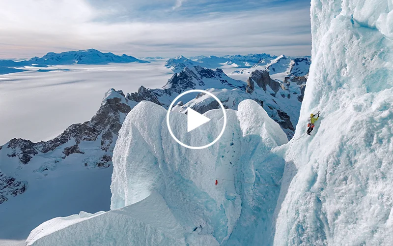 Panoramic view of almost vertical wall of snow and ice with tiny figure of person on it