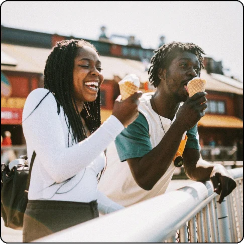 Image Description: A man and a woman eat ice cream cones while leaning on a railing.