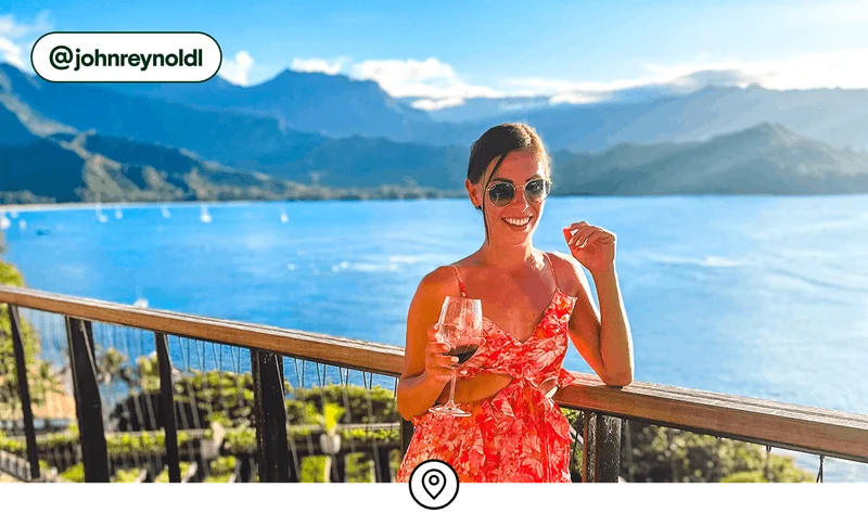 Image description: Woman with a glass of wine on a balcony overlooking the Pacific Ocean.