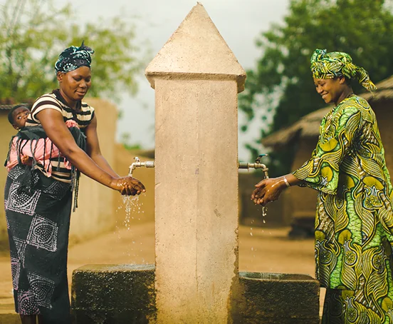 A photo of two young women washing their hands with clean water.