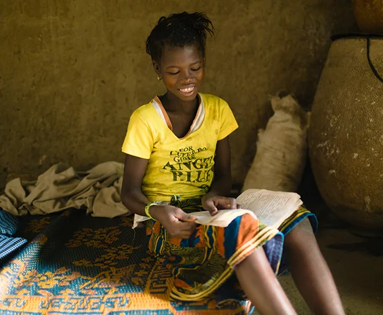 A photo of a young girl reading from a book.