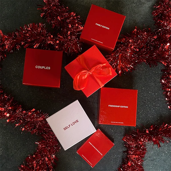 image of games from We're Not Really Strangers with some holiday tinsel around. The games are Family Edition, Couples, Friendship Edition, Self Love, and Honest Dating