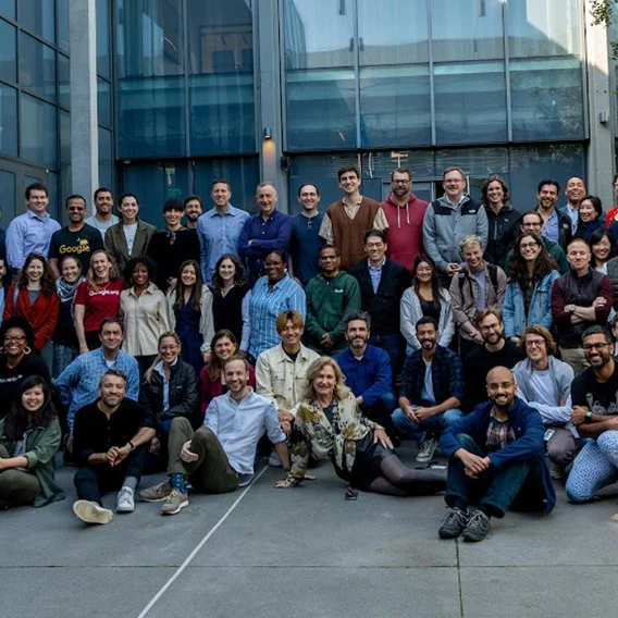 Photo of three rows of people looking into the camera and smiling.
