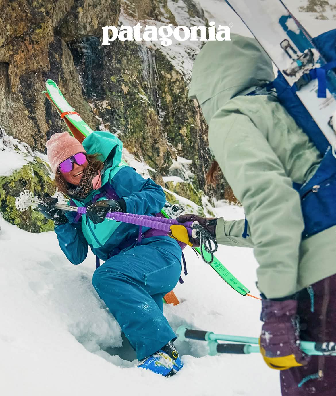 Patagonia. Worn Wear. A person helps another person out of the snow with ski poles.