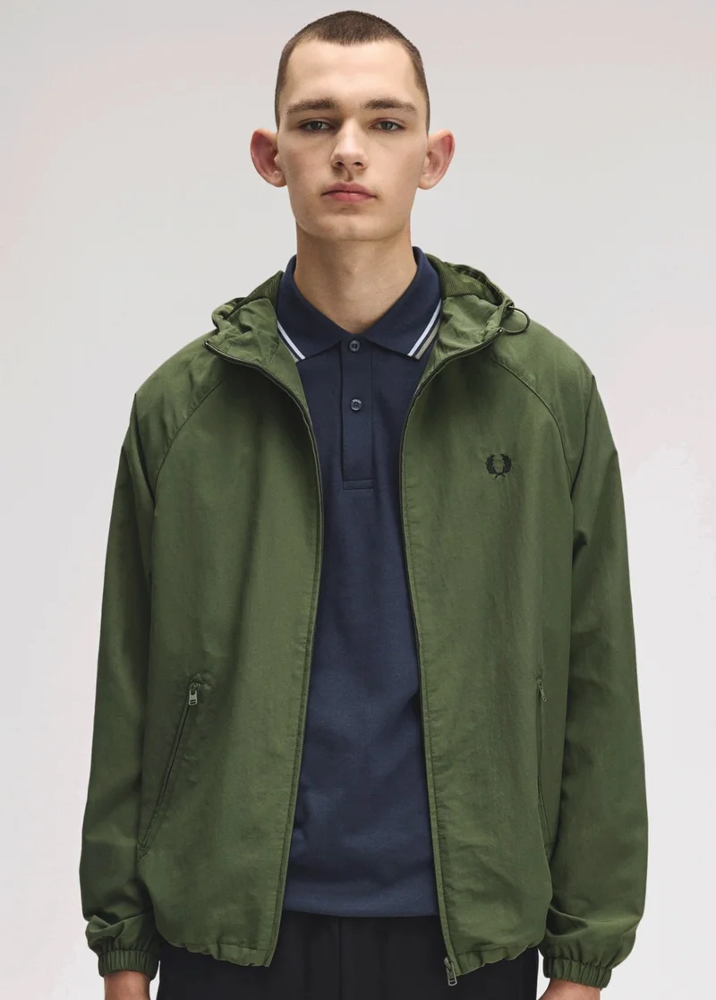 Male model wearing a Hooded Shell Jacket in Laurel Wreath Green and Fred Perry Shirt in Dark Airforce / Light Ice / Bay Leaf