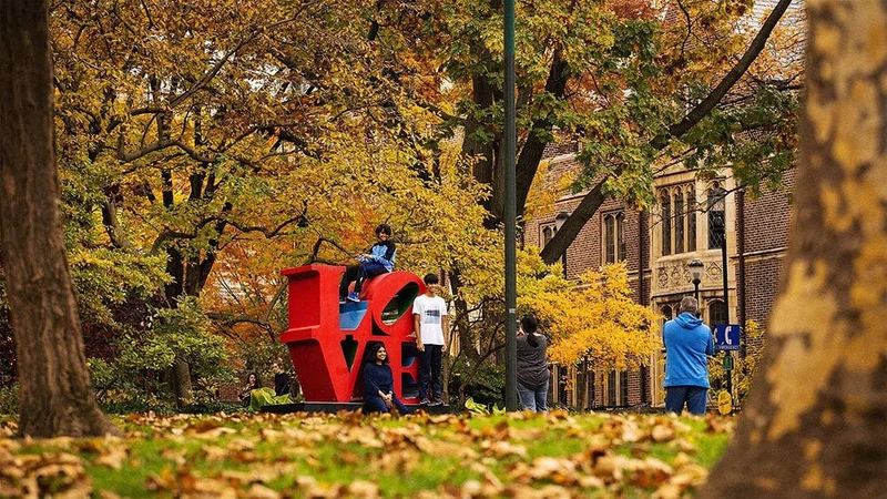 Image description: Family posing for photos at LOVE sculpture at the University of Pennsylvania.