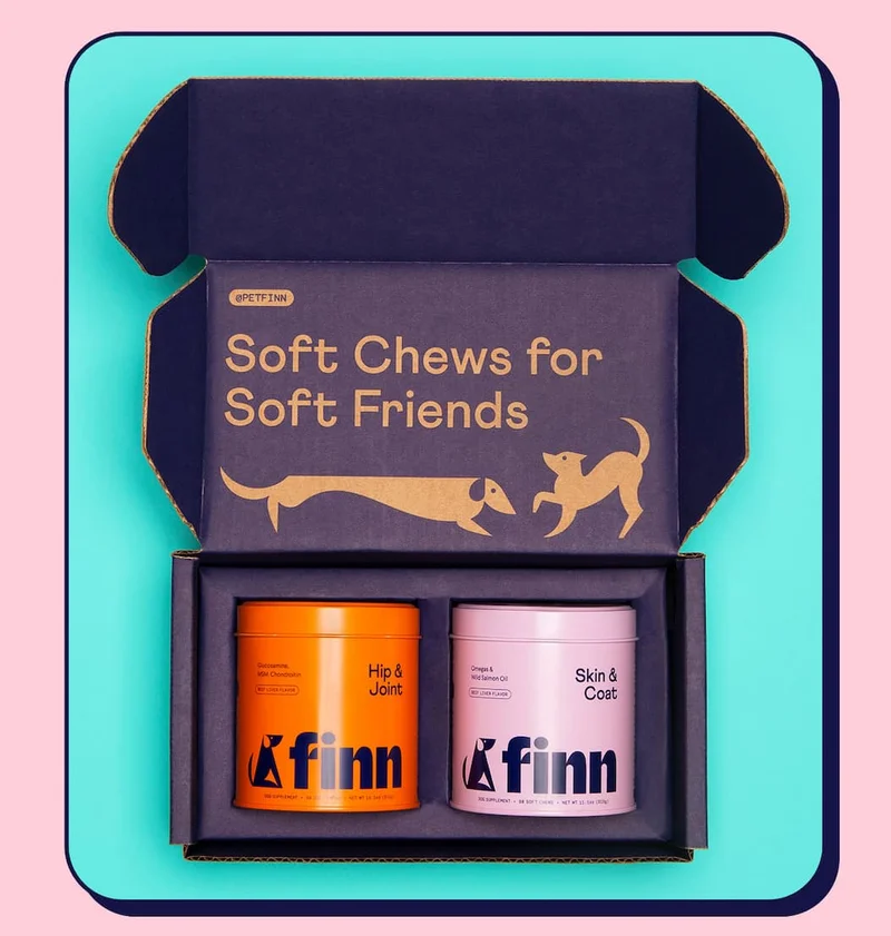 Overhead shot of two Finn tins in a shipping box with a header on the lid interior that says "Soft Chews for Soft Friends"