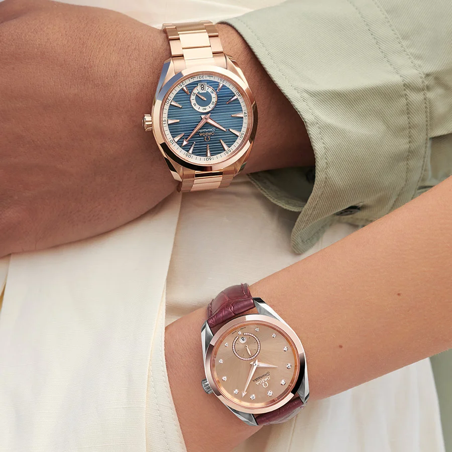 Two watches from the Aqua Terra Small seconds collection. One watch is 41 mm, has a blue dial and a Sedna™ Gold bracelet, while the other features a burgundy leather strap, a Steel ‑ Sedna™ gold case and a Linen dial, both displayed on the wrists of two people.