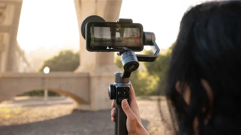Image of filmmaker shooting a bridge with a phone and moment lens on a handheld gimbal.