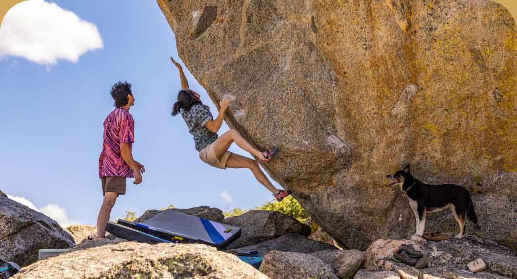 Two people bouldering in colorful shirts.