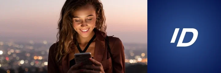 A young woman smiles as she looks at her smartphone.