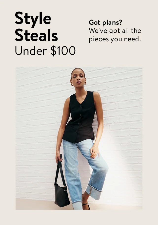 A woman wearing a black sleeveless top with blue jeans and black flats.