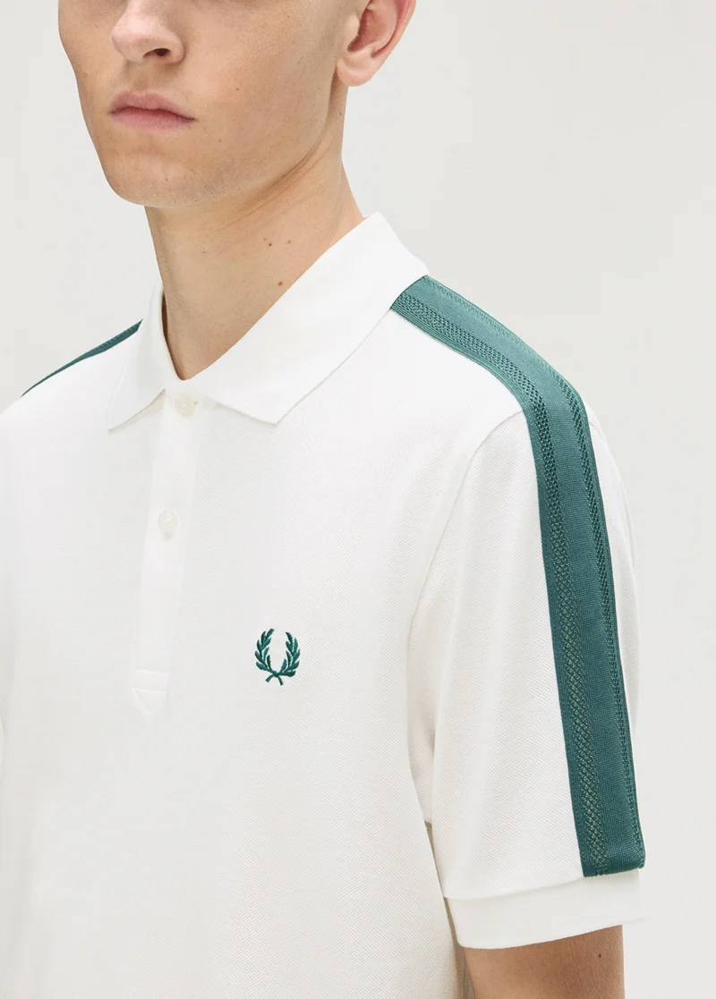 A close up shot of a model wearing a Fred Perry Mesh Taped Polo Shirt in White