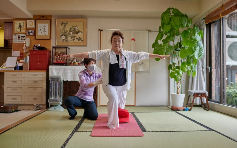 A middle-aged Japanese woman balancing as she does a lunge exercise.