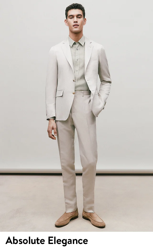A model wearing a light-tan suit, pale sage shirt and tan slip-on shoes.