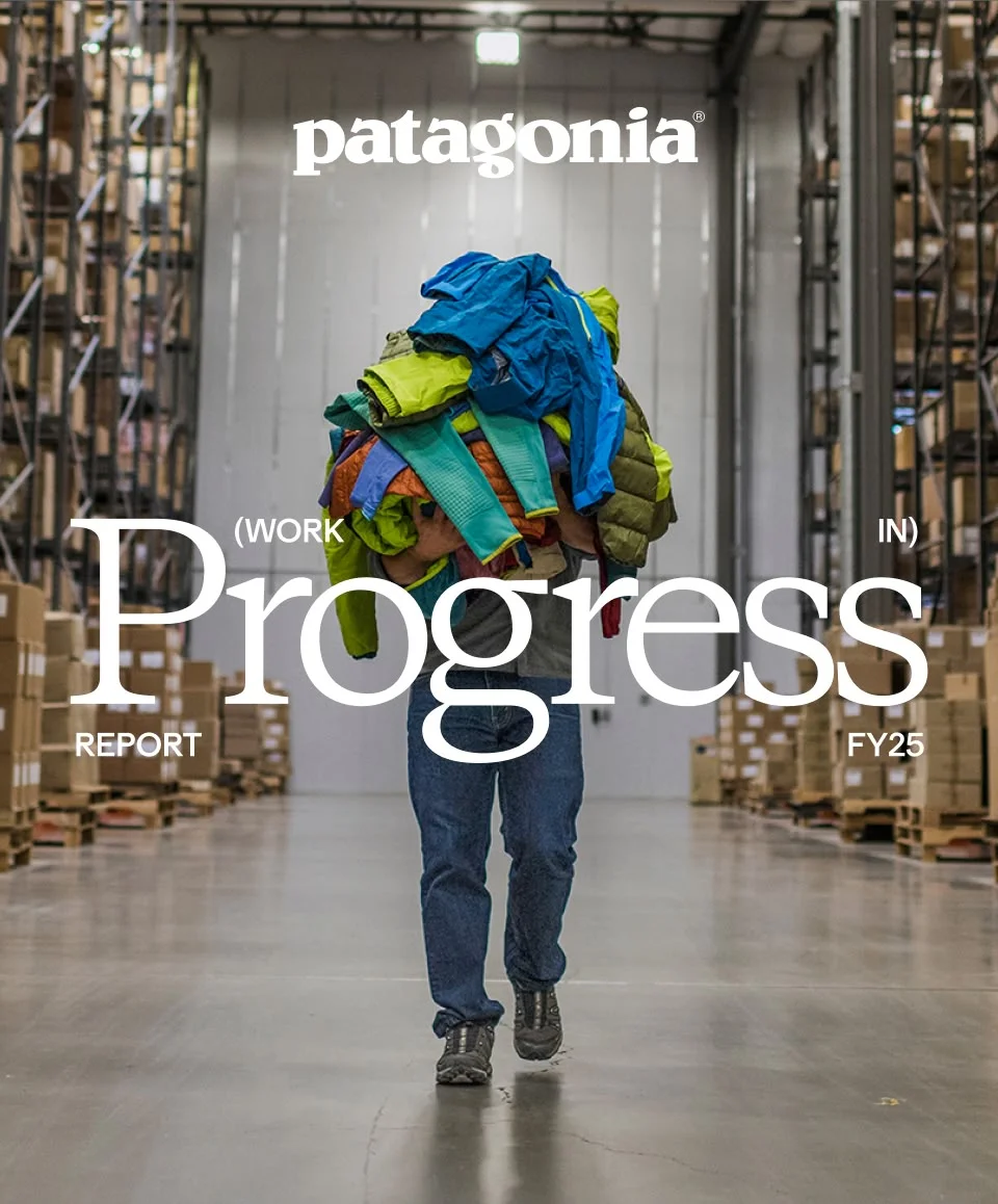 A person walking in a warehouse holding a pile of clothes.