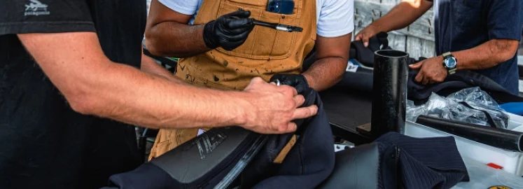 Wetsuit repair technicians evaluate a piece.