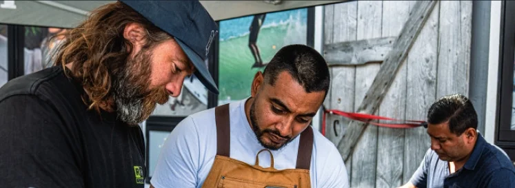 Wetsuit repair technicians evaluate a piece.