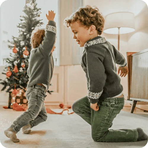two brothers playing and making holiday memories with christmas tree in background two brothers playing and making holiday memories with christmas tree in background