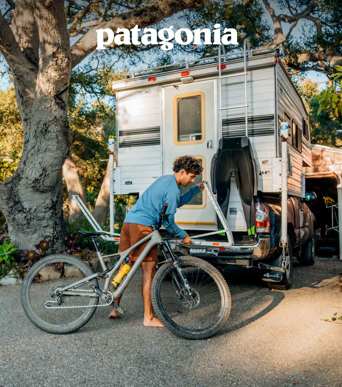 A person putting a mountain bike on a rack on the back of their truck.