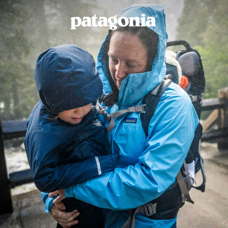Patagonia. A person with two kids standing in the spray from a waterfall.