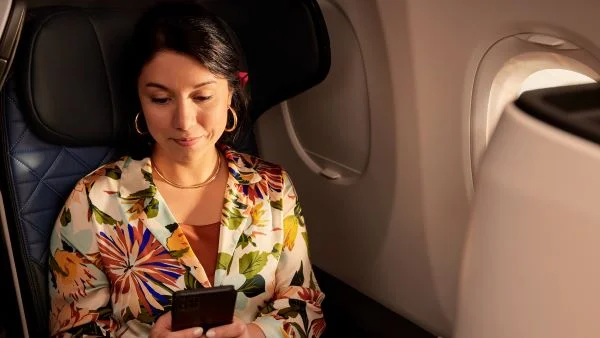 A woman uses her mobile device onboard a Delta plane.