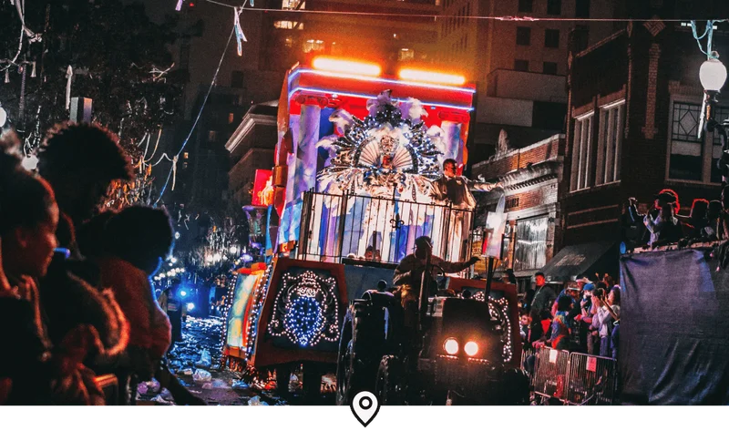 Image Description: A brightly lit parade float rolling through the French Quarter in New Orleans