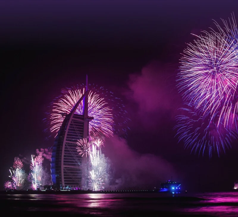 Image Description: A landscape view of New Year’s fireworks in the night sky over the Burj Al Arab in Dubai