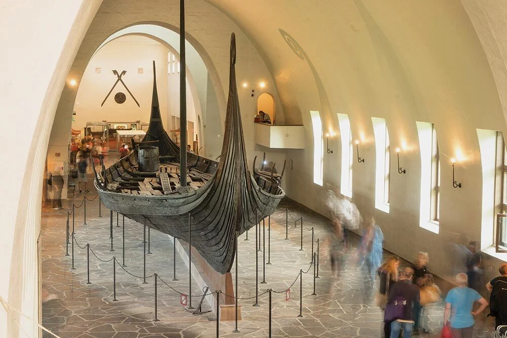People in a museum walk past a Karve, a type of Viking longship that could be both sailed and rowed.