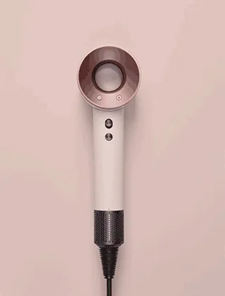 The Dyson Supersonic hair dryer in Ceramic pink and rose gold being revealed by silk