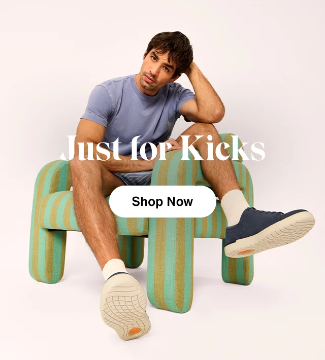 Man sitting wearing blue T-shirt, shorts and Benji sneaker in Navy. Shop Men’s Shoes.