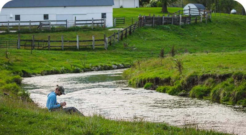 A person sitting on the bank of a river.