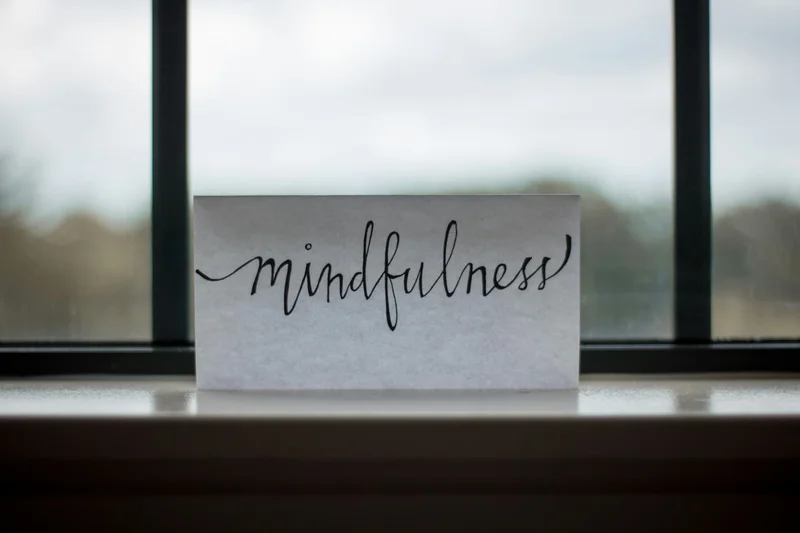 A white sign with black cursive lettering that says “mindfulness.”