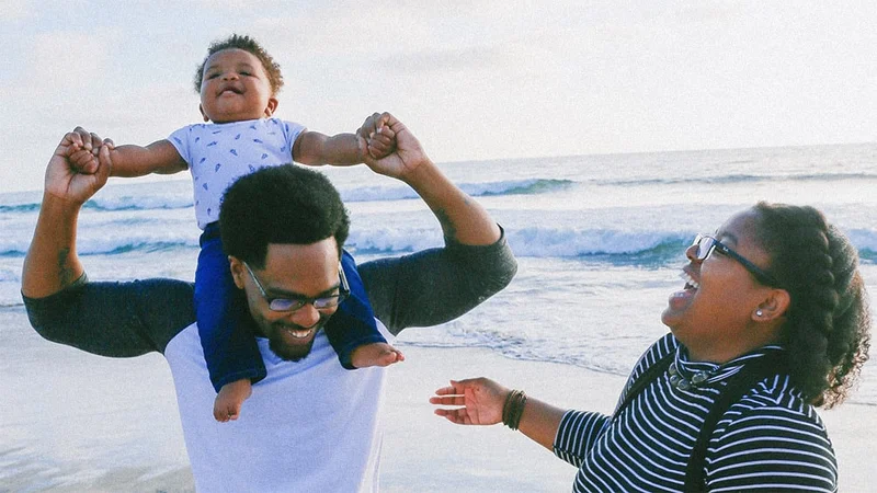 Image description: A family laughing together on the beach