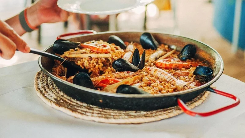 Image description: Man serving paella, in a restaurant in Mallorca