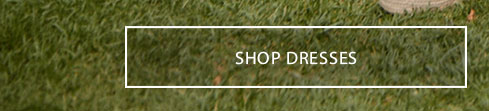 White outlined button with "SHOP DRESSES" text on a vibrant green grass background. Explore our beautiful new collection of dresses now.