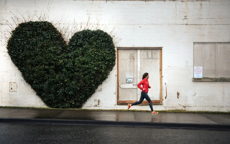 A woman jogs past a heart-shaped vine in Bellingham, Washington. Emerging research shows that low-intensity exercise, known as Zone 2 training, can help the body burn fat more efficiently and build metabolic flexibility—crucial for energy management and long-term health.