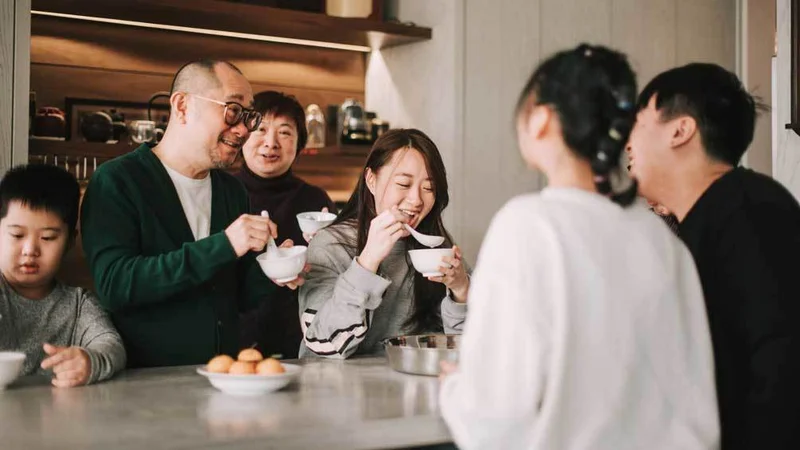 Image description: Multi-generation Chinese family enjoying glutinous rice ball, Tang Yuan, dessert during lunar new year festival.