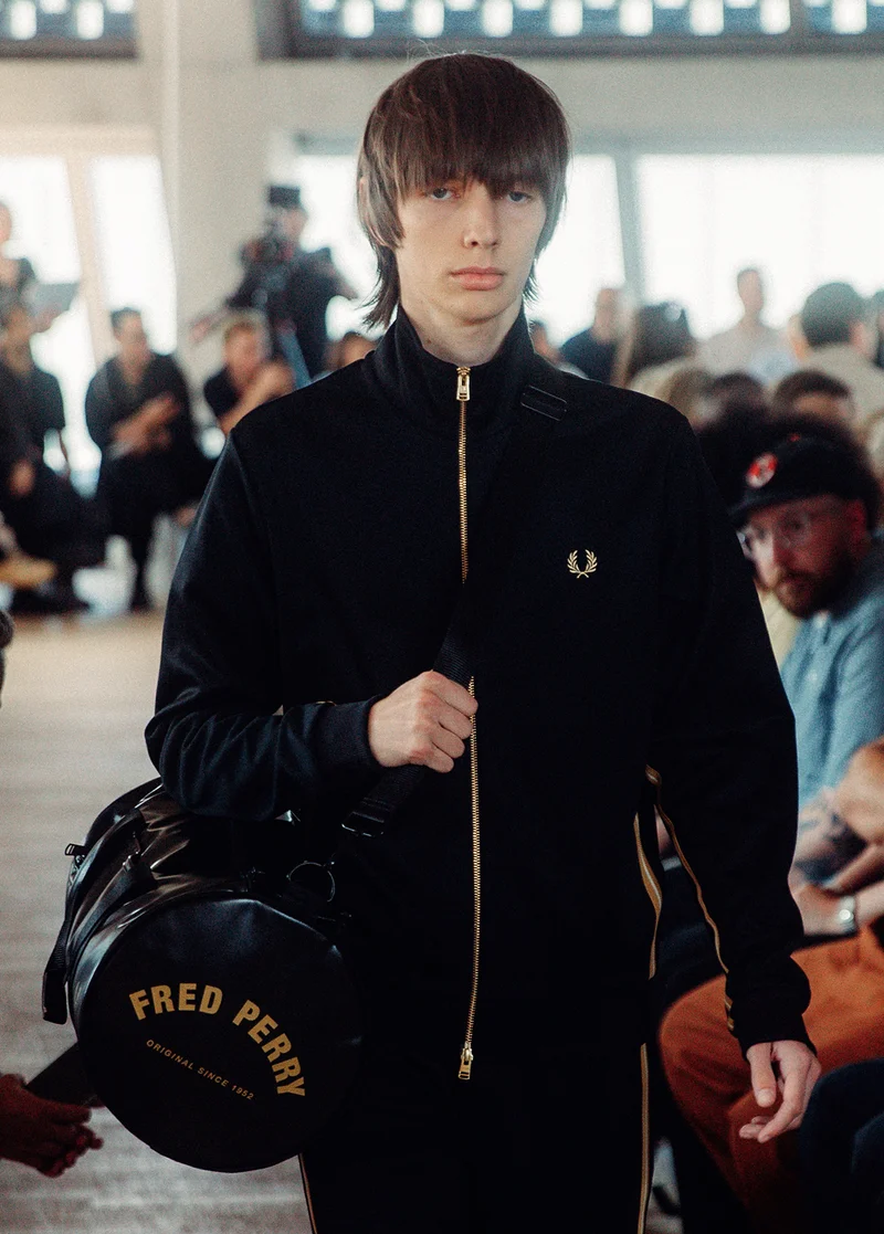 Male model wearing a Fred Perry Stripe Tape Track Jacket in Black / Champagne