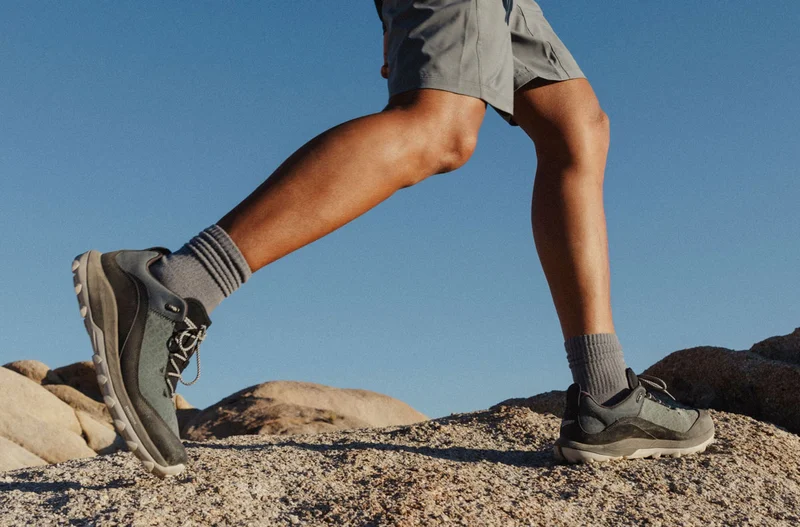 Close-up of a man's legs wearing the new N45 hiking boots in the color Spruce, hiking across rugged desert terrain.