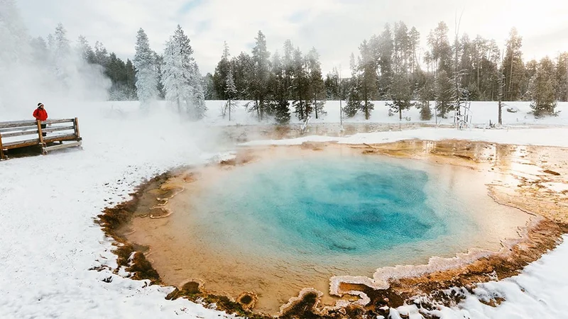 Image description: Woman visiting hot spring in Yellowstone National Park, in the winter