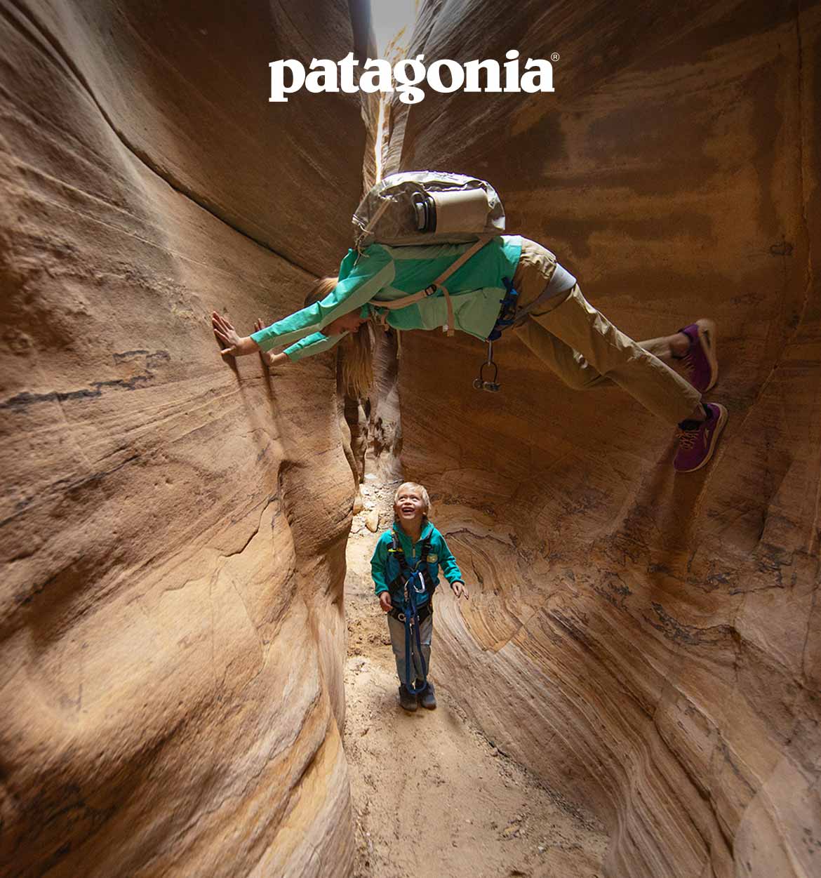 Patagonia. A person climbing between rocks with another person.